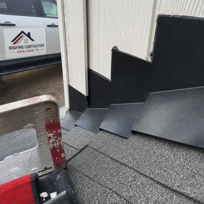 Stepped metal flashing at the base of a wall above shingles